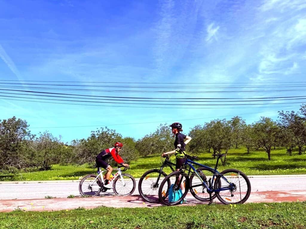 Cyclists resting with bikes on a scenic rural road in Portugal.