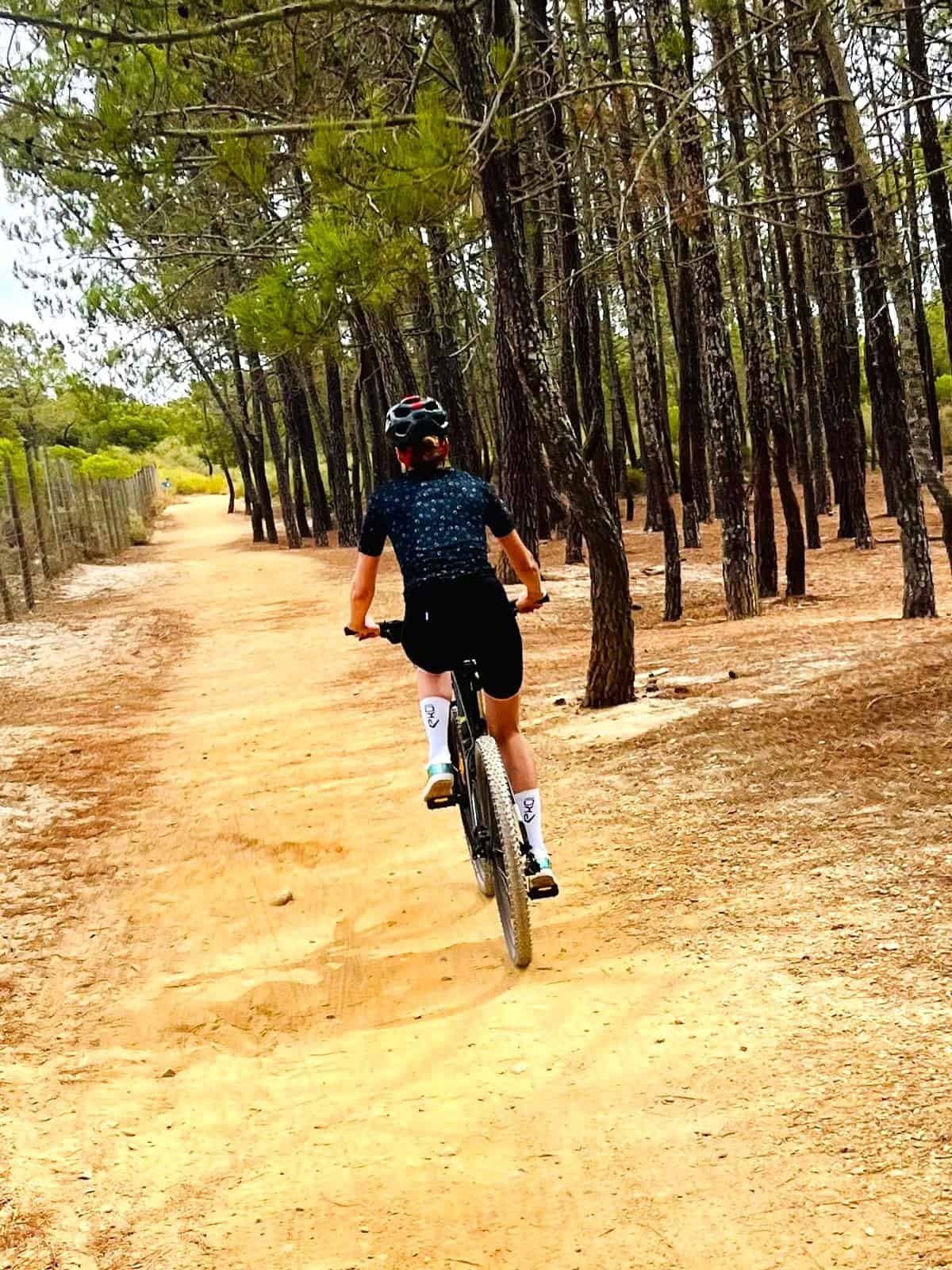 Cyclist riding a mountain bike through a wooded trail during a scenic ride.