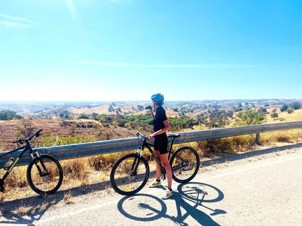Cyclist enjoying a scenic ride along a rural landscape with hills in the background.