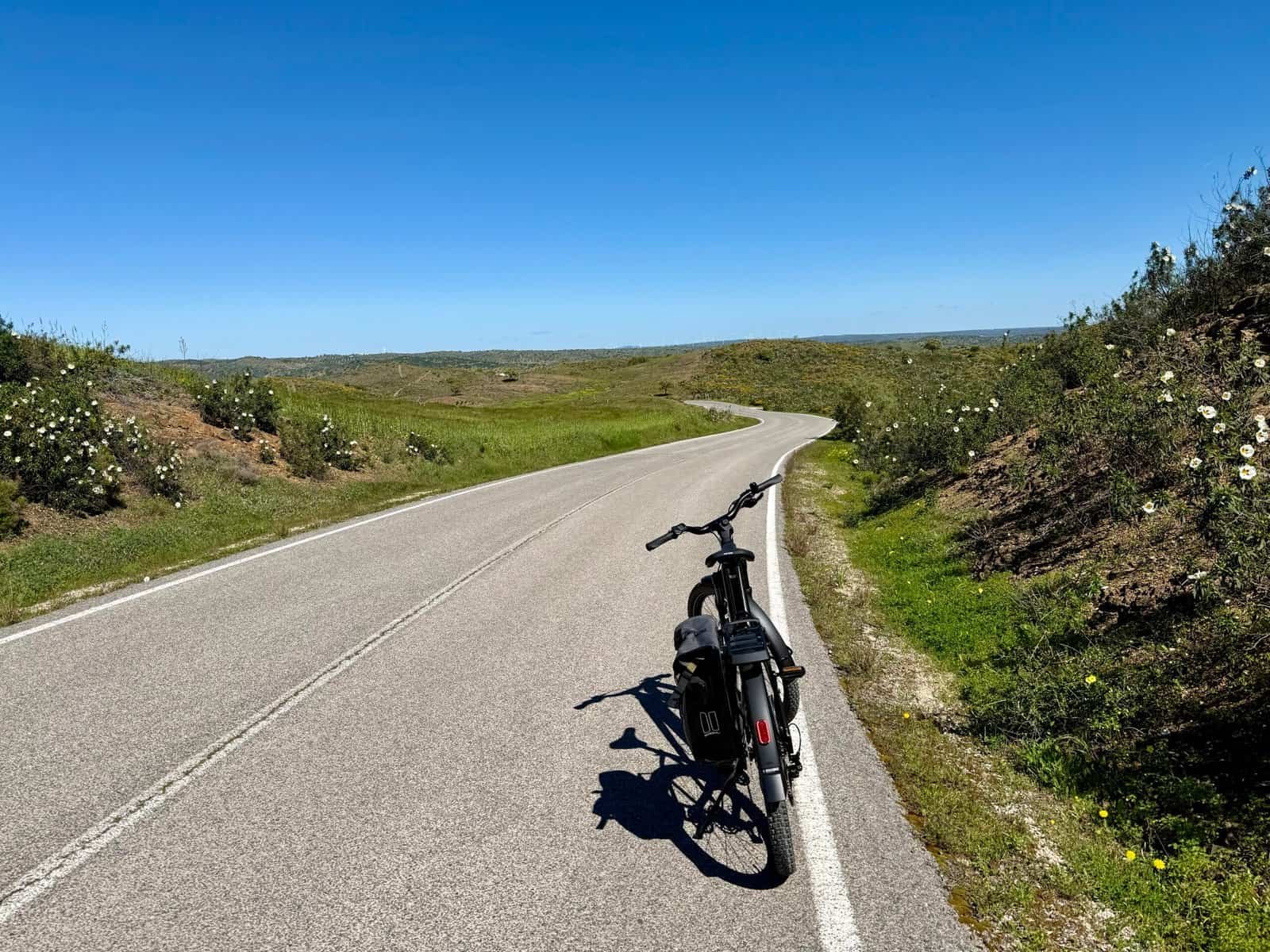 Algarve cycling ride with a bicycle on a peaceful, winding road under a clear blue sky.